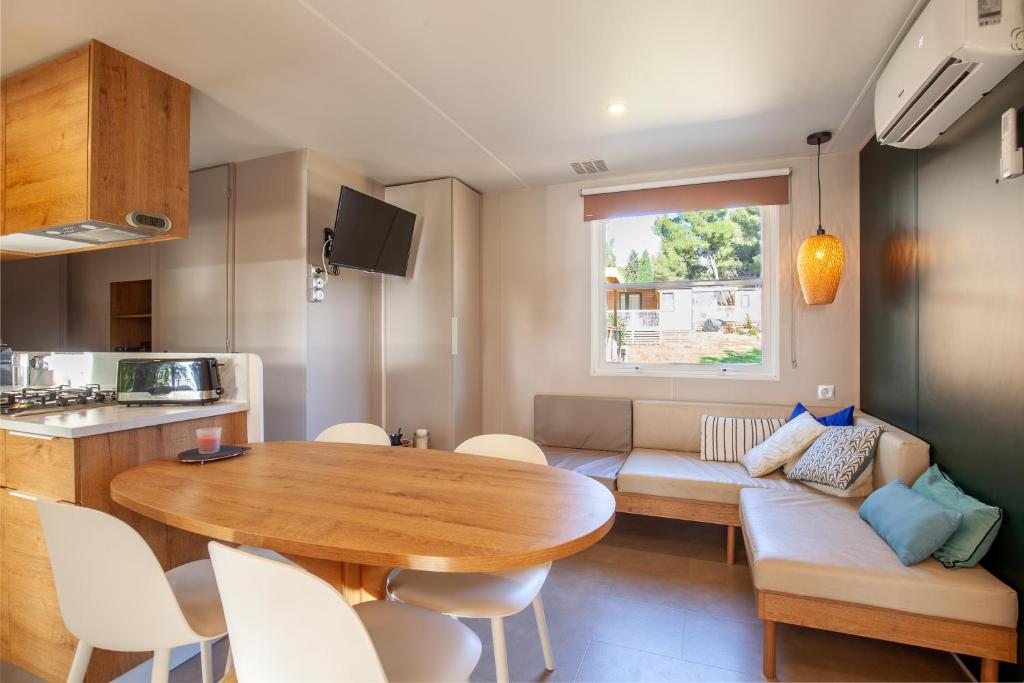 eine Küche und ein Wohnzimmer mit einem Tisch und einer Couch in der Unterkunft Camping Lou Soulei 218 in Carry-le-Rouet