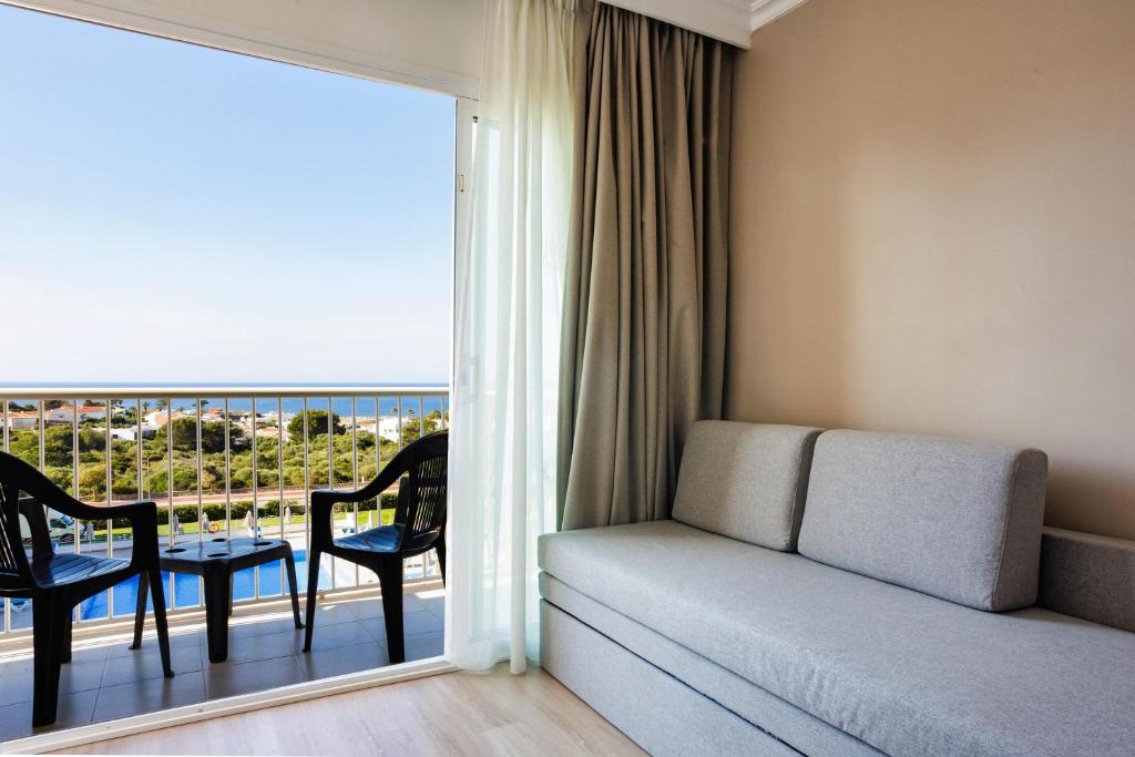 a room with a couch and a balcony with a view at Minura Sur Menorca in Punta Prima