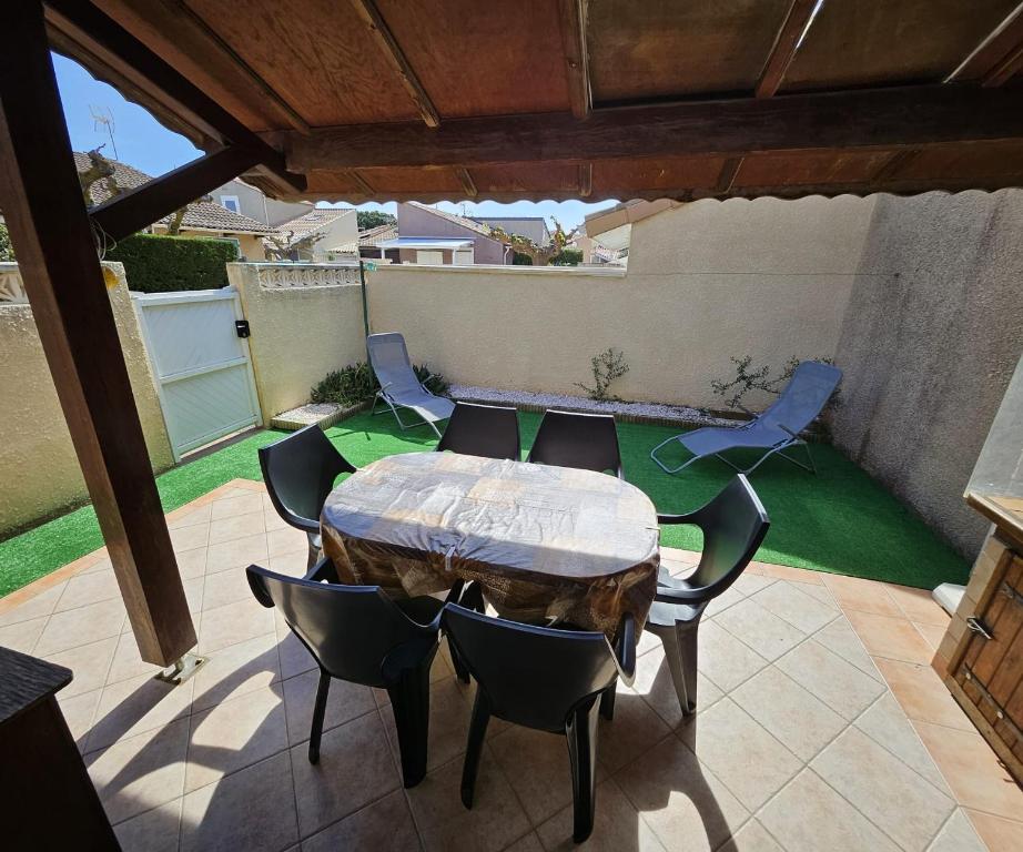 un patio avec une table et des chaises sur un patio dans l'établissement Jolie maison de vacances rénovée toute climatisée 6 couchages, 2 chambres mezzanine 100m de la plage residence LE VILLAGE DE LA MER LRVM88, à Portiragnes