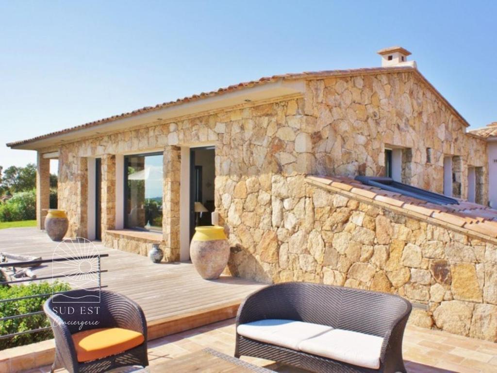 une maison en pierre avec une terrasse et des chaises dans l'établissement Villa Petra Vuer Mer & Piscine, à Zonza