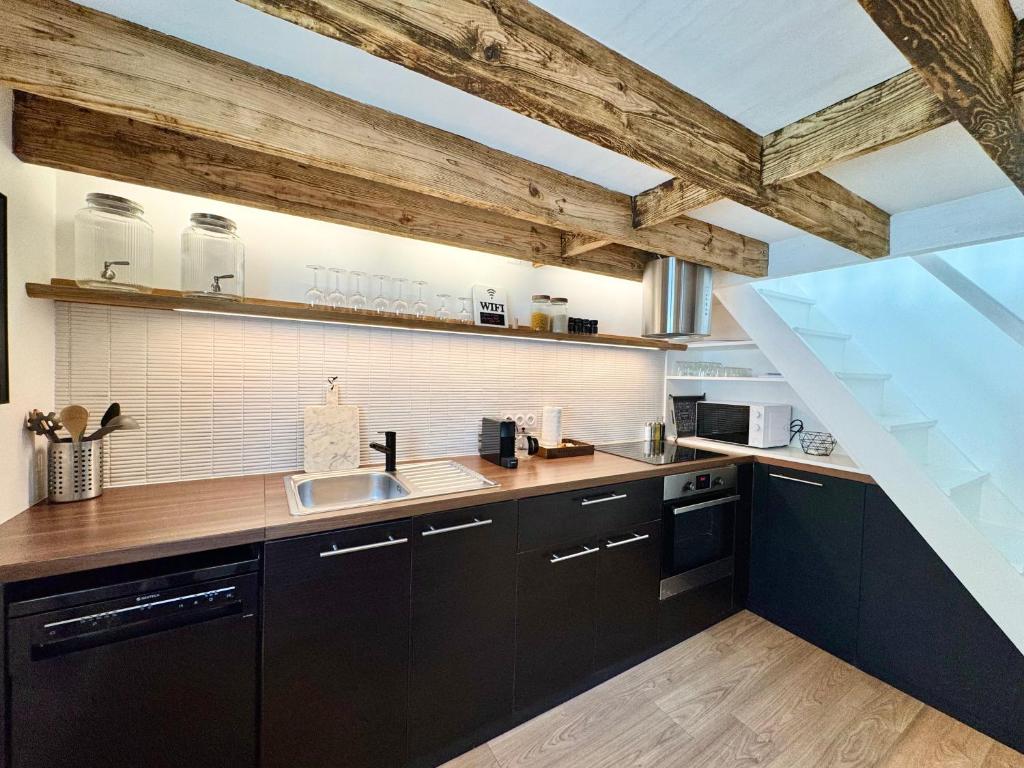 a kitchen with black cabinets and wooden ceilings at La Maison Diderot, Centre de Rennes in Rennes