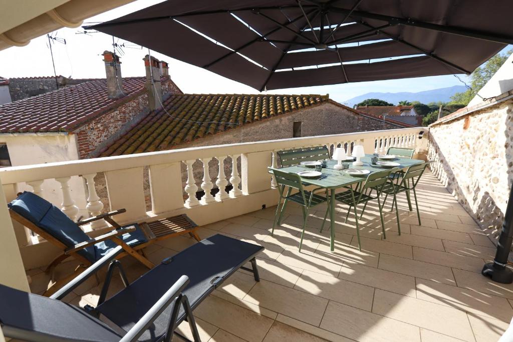 un patio avec tables et chaises sur un balcon dans l'établissement Superbe maison avec terrasse a quelques minutes des plages, à Latour-Bas-Elne