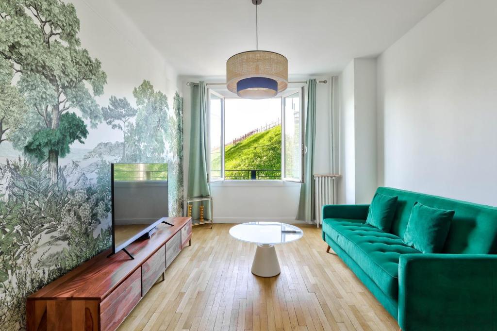 - un salon avec un canapé vert et une télévision dans l'établissement GuestReady - Charming Stay in Montsouris, à Paris