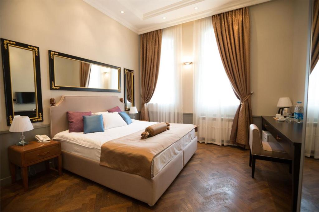 a bedroom with a large bed and a desk and window at Seven Rooms Boutique Hotel in Baku