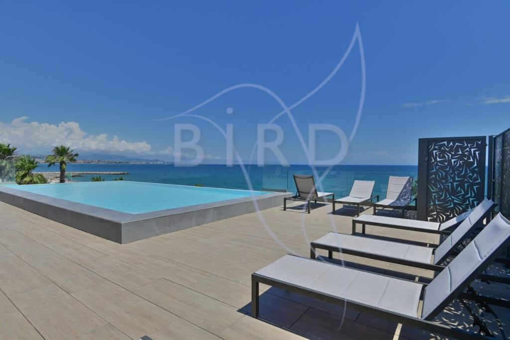 - une piscine avec des chaises longues à côté de l'océan dans l'établissement Studio feet in the water friendly cozy and unique, à Villeneuve-Loubet