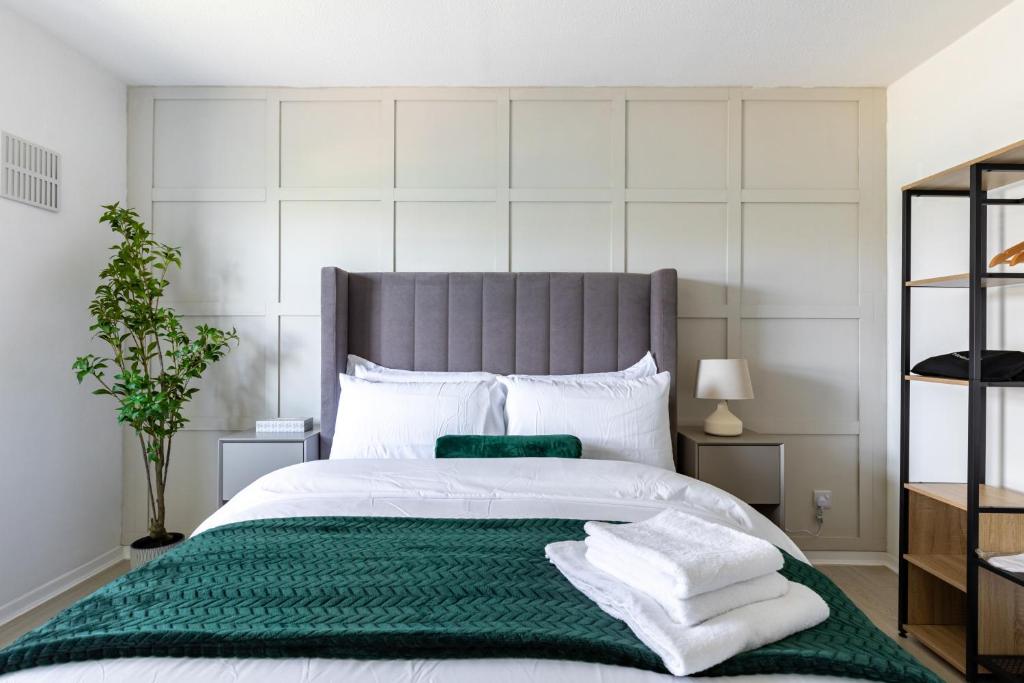 a bedroom with a large bed with a green blanket at West London Apartment - Near Heathrow & Twickenham Rugby Stadium in Hounslow