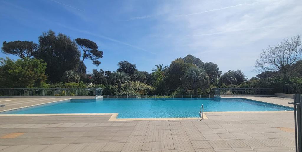 une grande piscine bleue avec des arbres en arrière-plan dans l'établissement Nice 2 room with pool and balcony in Fréjus, à Fréjus