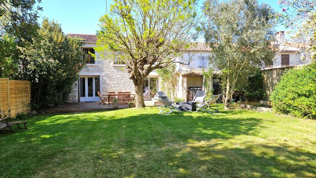 a house with a yard with chairs and a tree at La Maison de la Venise Verte - 4 chambres, jardin in Le Mazeau