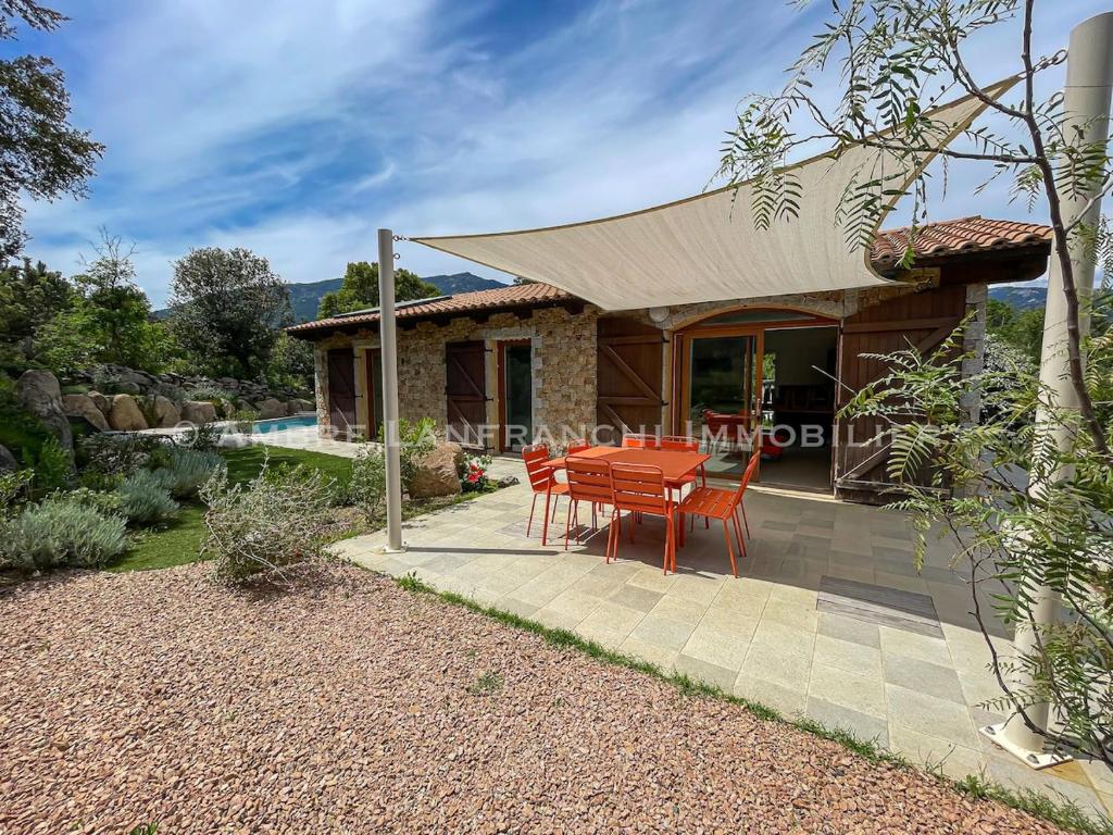 une maison avec une table et des chaises sur une terrasse dans l'établissement Maison en pierre - 6 personnes - piscine, à Porto-Vecchio