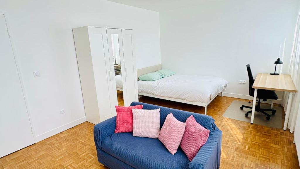 - un salon avec un canapé bleu et des oreillers roses dans l'établissement Apartement 8 personnes, 4 lits Créteil, metro 20 min de Paris, à Créteil