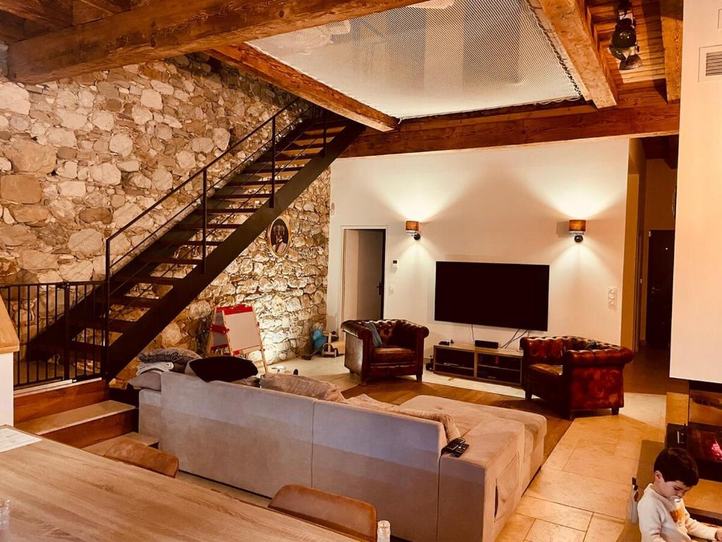 - un salon avec un grand canapé et un mur en pierre dans l'établissement Ferme rénovée, à La Celle-sous-Gouzon