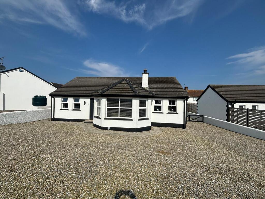 a white house with a gravel driveway in front of it at Coastal Escape - Portballintrae in Portballintrae