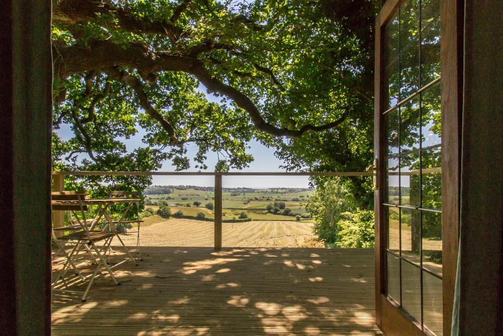 an open door to a porch with a view of a field at Extraordinary Huts Ltd in Rye