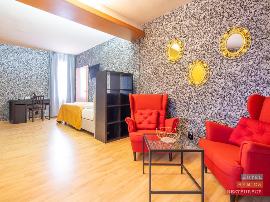 sala de estar con sillas rojas y cama en Hotel Benica, en Benešov