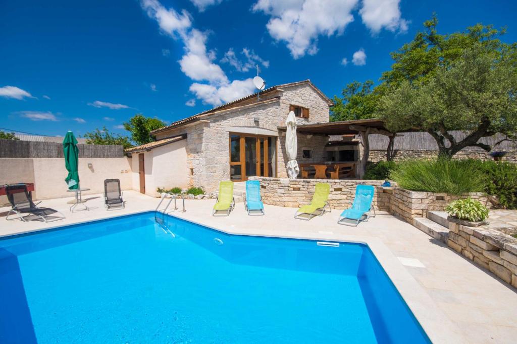 a swimming pool with chairs and a house at Villa Irena, a romantic villa nestled in the heart of Istria in Pulići