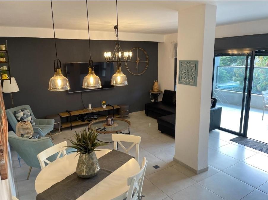 a dining room and living room with a table and chairs at Welcome to Sunshine in Migdal