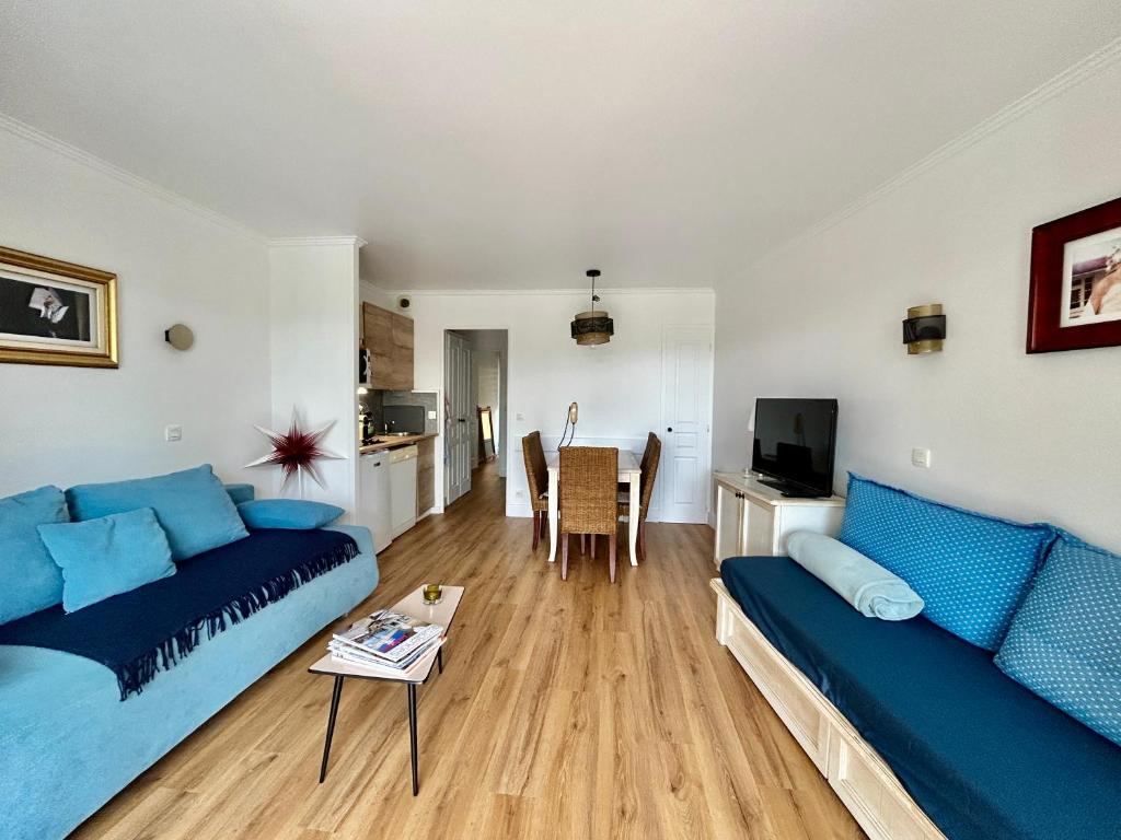 un salon avec un canapé bleu et une table dans l'établissement Les Restanques Lavandes 2009 rez de jardin, à Grimaud