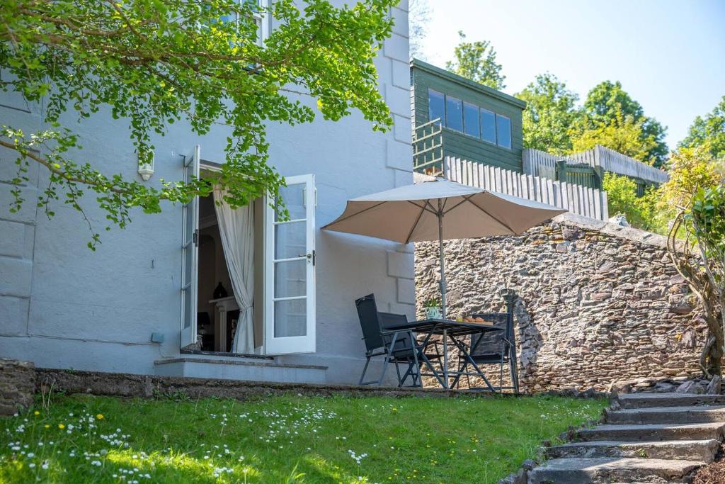 ein Tisch mit Sonnenschirm vor einem Haus in der Unterkunft Townhouse With Garden, Parking & River Dart Views in Dartmouth
