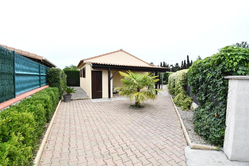 une passerelle en briques devant une maison dans l'établissement Maison 6 personnes climatisée dans résidence avec piscine à 900 M des plages, à Vendres-Plage
