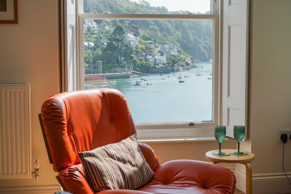 an orange chair sitting in front of a window at Riverside Apartment with Stunning Views & Patio in Dartmouth