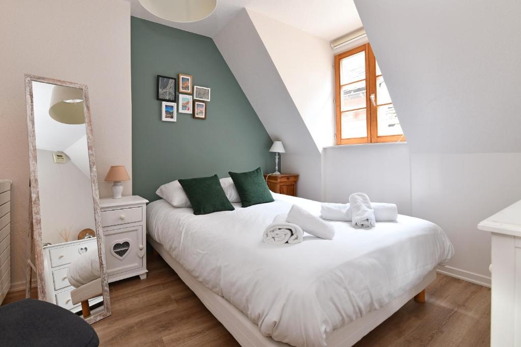 a bedroom with a bed with white sheets and green pillows at Appartement Beraweka avec Climatisation et Salle de Sport in Colmar