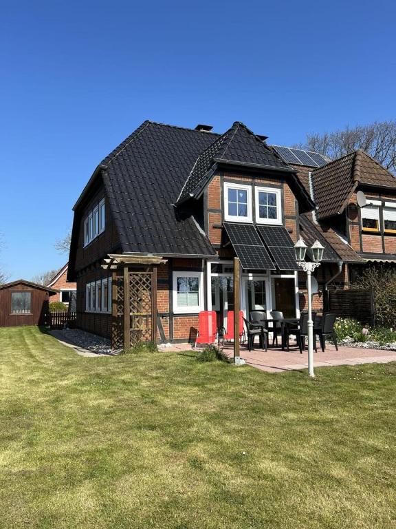 a house with a black roof and a yard at 58 Ferienhaus Sonnenblick in Avendorf auf Fehmarn