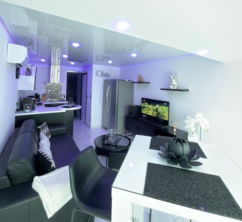 un salon violet avec un canapé et une télévision dans l'établissement Portnature 571 Cap d'Agde Naturiste, au Cap d'Agde