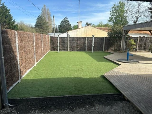 un jardin avec de l'herbe verte à côté d'une clôture dans l'établissement Maison familiale au calme non loin de la mer, à Bretignolles-sur-Mer