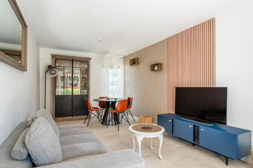un salon avec un canapé, une télévision et une table dans l'établissement La Saltarelle Appartement moderne 750m du port, à Cassis