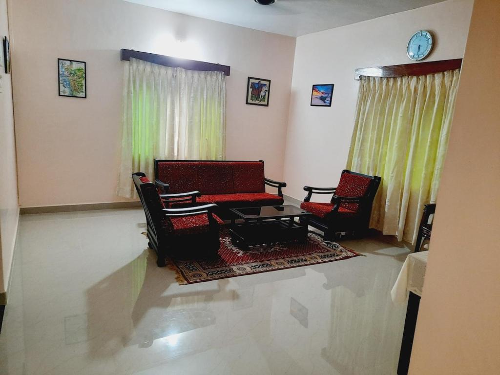 sala de estar con sillas, mesa y reloj en Villa Louisana-Being Goan, en Varca