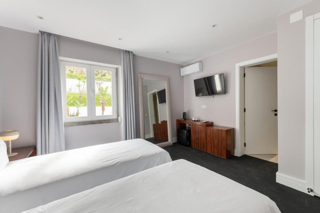 A twin bedroom with two beds, a street-facing window and wall-mounted television.