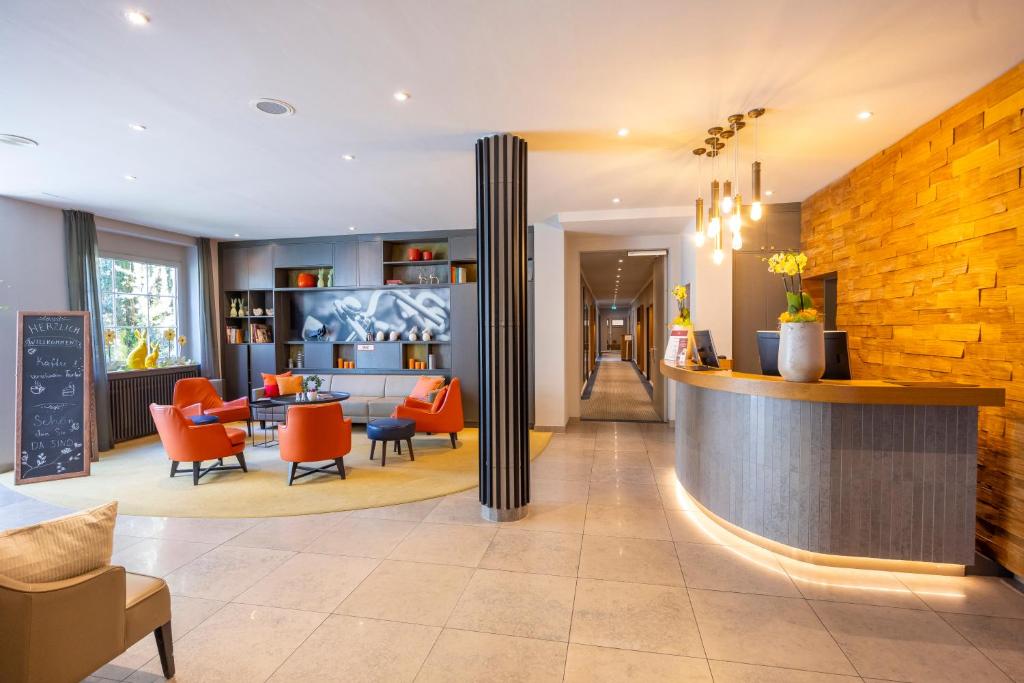 una hall di un hotel con sedie arancioni di Parkhotel Hohenfeld Münster a Münster