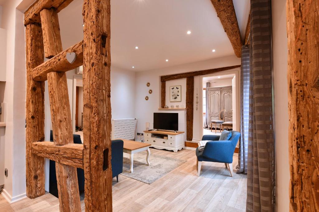a living room with a table and chairs and a television at Appartement Bredala avec Parking et Climatisation in Colmar