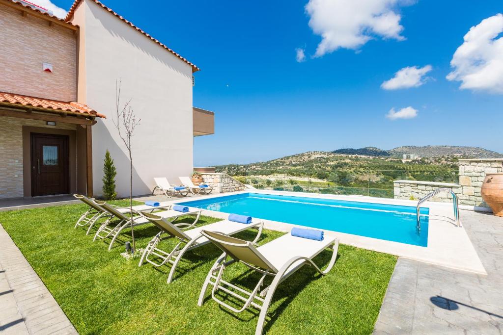 een villa met een zwembad en lawnitures bij Renta Villas, vivid experience, By ThinkVilla in Perama