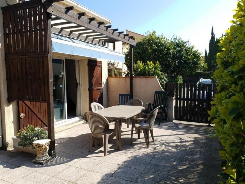 une table et des chaises assises sur une terrasse avec un parasol dans l'établissement Maison de vacances climatisée, à Argelès-sur-Mer