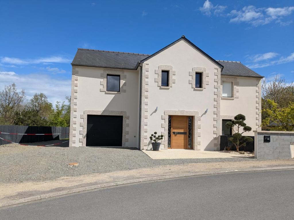 une maison blanche avec un garage dans une rue dans l'établissement Maison familial dans le golf, au Tronchet