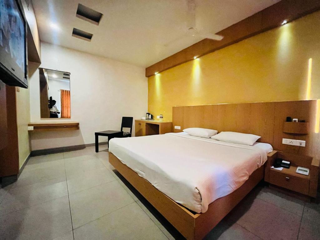 a bedroom with a large bed with a wooden headboard at PLA Rathna Residency Trichy in Tiruchchirāppalli