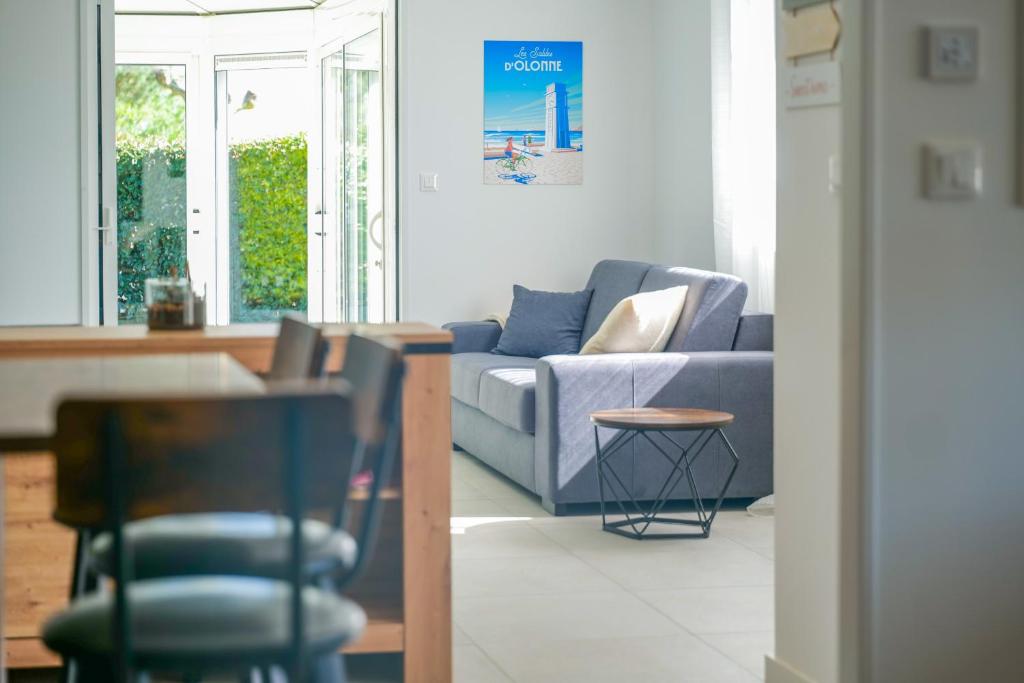un salon avec un canapé bleu et une table dans l'établissement maison lumineuse avec veranda et jardin - 8 personnes, à Les Sables-dʼOlonne