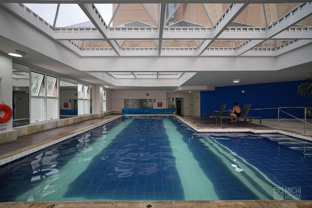 a large swimming pool with a person sitting in a chair in a building at Maravilhoso Flat na Av Principal de Alpha AC/WF in Aldeia