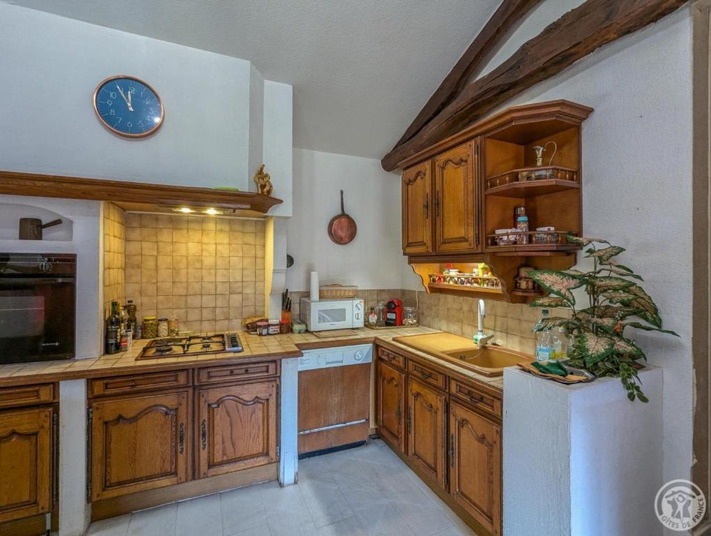 a kitchen with wooden cabinets and a clock on the wall at Villa jean-marie in Sengouagnet