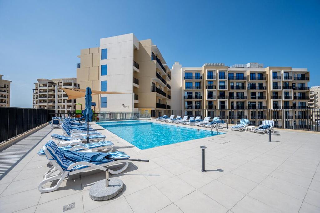 a swimming pool with lounge chairs on a building at Private Beach 1BR-Yacht Club-Work Space-Pool-Gym in Ras al Khaimah