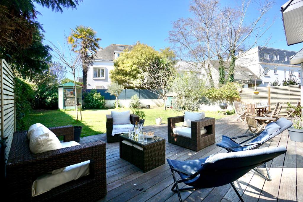 une terrasse en bois avec des chaises et des meubles. dans l'établissement Villa Armor - 400m de la mer -, à Larmor-Plage