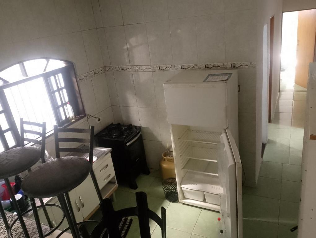 a small kitchen with an empty refrigerator and chairs at Sua paz está aqui in Mongaguá