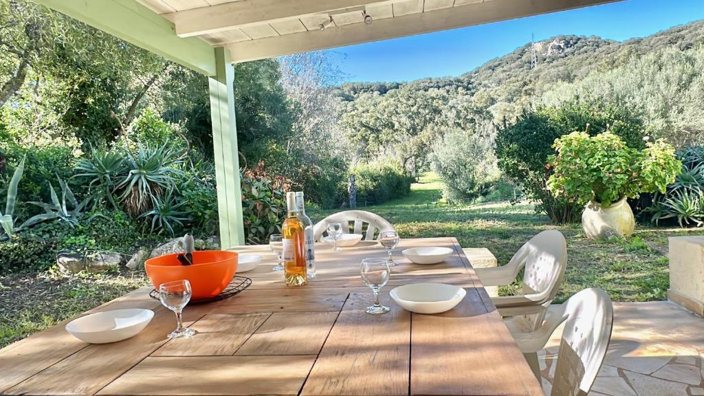 - une table en bois avec des verres à vin sur la terrasse dans l'établissement VILLA située à 7 minutes du centre-ville de Porto-vecchio, à Porto-Vecchio