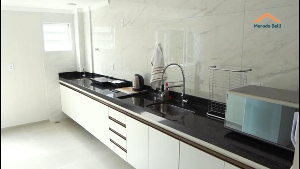 a kitchen with a sink and a black counter top at Morada Belli - Apartamento no Centro in Serra Negra