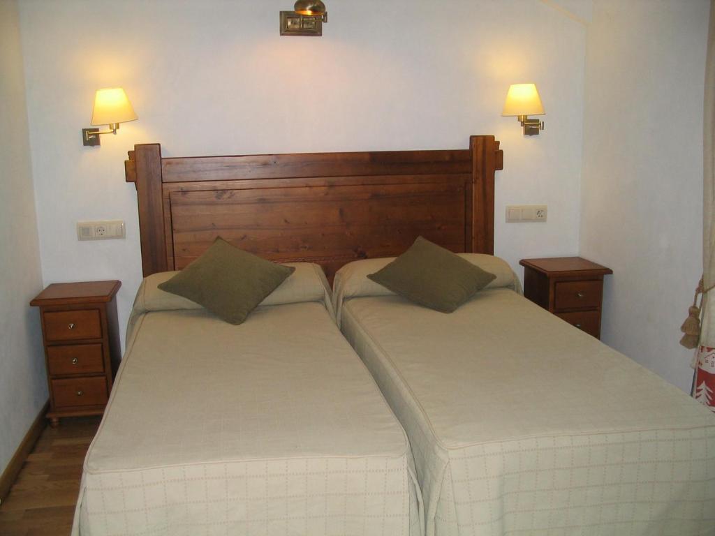 two beds in a bedroom with two lamps on the wall at Villa Russell Hotel&Apartments in Torla-Ordesa