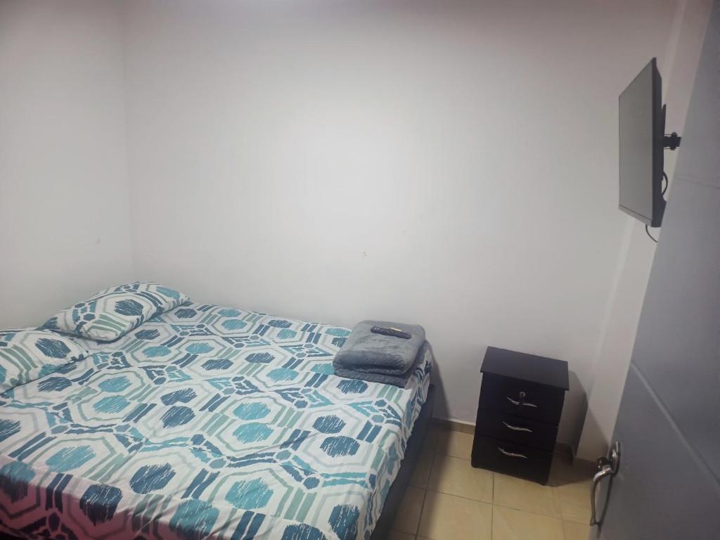 a bedroom with a bed with a comforter and a night stand at La fonda in Santa Rosa de Cabal