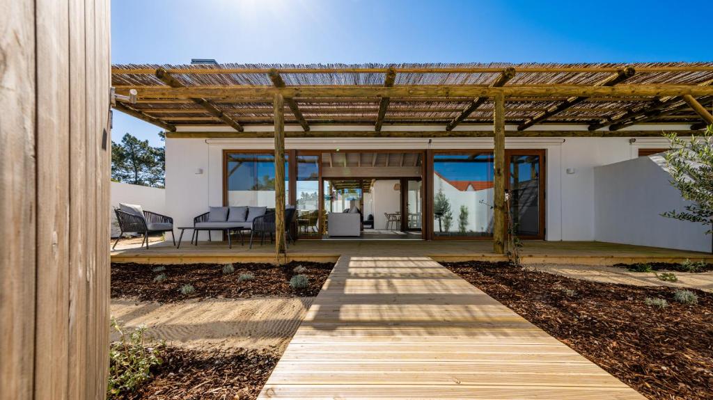 una pasarela de madera que conduce a una casa con pérgola en Pestana Comporta Village Residences, en Comporta