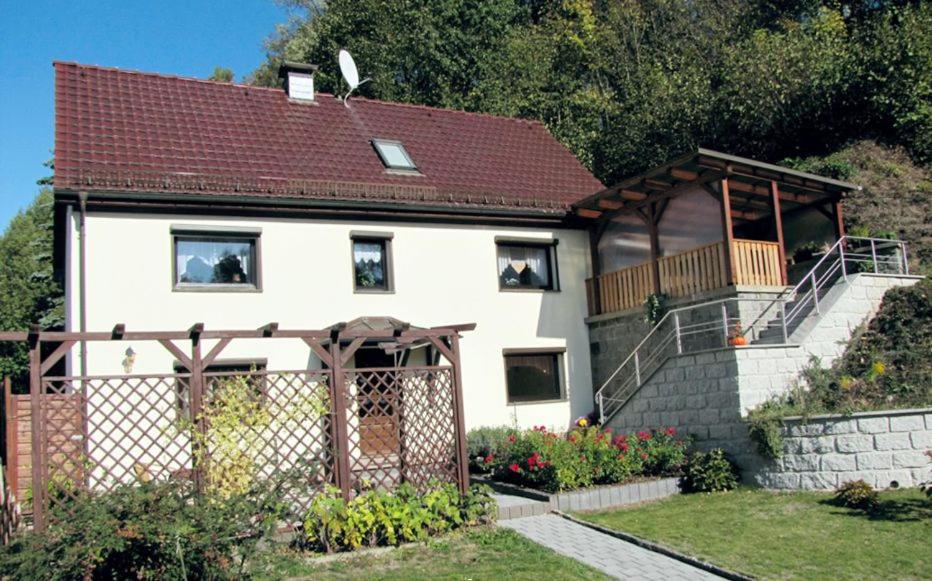 a white house with a balcony and a fence at Ferienwohnung Schade in Hohnstein