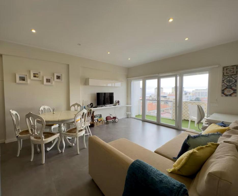 a living room with a couch and a table and chairs at GuestReady - Seaview in Costa da Caparica in Costa da Caparica